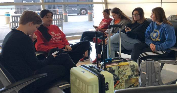 photo of students waiting in airport with luggage
